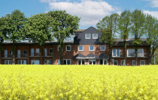 Aussenansicht Strandhotel mit Rapsfeld im Vordergrund